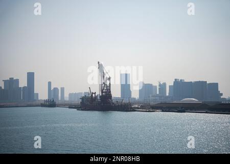 Ein riesiges Gebäude, viele Turmbaustellen mit Kränen und Gebäuden neben dem Parkplatz und dem Meer. Blick von der Bootstour. Abo Dhabi, Vereinigt Euch Stockfoto