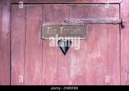 Bild einer Holztür einer antiken Toilette mit einem Schild mit den deutschen Wörtern Fuer Frauen für Frauen Stockfoto