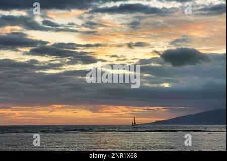 Ruhige Sonnenuntergangsszene eines Segelboots, das über den Horizont gleitet. Stockfoto
