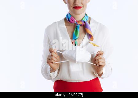 Nahaufnahme einer stilvollen weiblichen Stewardess isoliert auf weißem Hintergrund in Uniform mit FFP2 Maske. Stockfoto