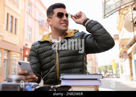 Ein Mann, der im Café im Freien Hörbücher hört Stockfoto