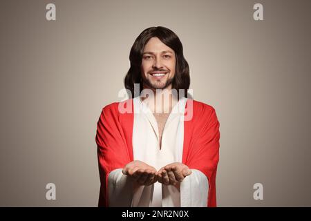 Jesus Christus streckt seine Hände auf beigefarbenem Hintergrund aus Stockfoto