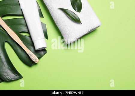 Zahnpasta, Bürste, Blätter und Handtuch auf hellgrünem Hintergrund, flach gelegt. Platz für Text Stockfoto