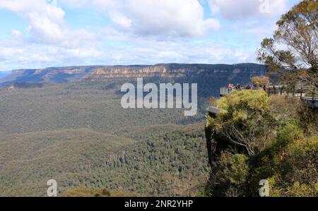 Touristen am Echo Point erscheinen im Gegensatz zur Weite des Blue Mountains National Park in Miniaturform. Stockfoto