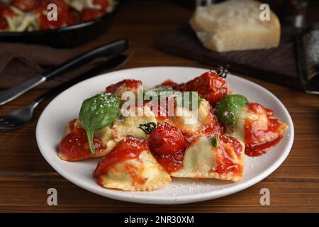 Leckere Ravioli mit Tomatensauce, serviert auf einem Holztisch Stockfoto