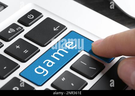 Frau drückt blauen Knopf mit WORTSPIEL auf der Tastatur, Nahaufnahme Stockfoto