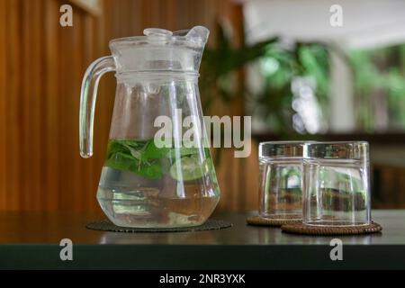 Entgiftungswasser aus Gurken, Limette und Minzblättern in der Kanne im Lounge-Bereich Stockfoto