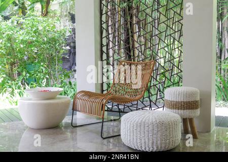 Halb geöffneter Loungebereich mit allen natürlichen Materialien, Möbel, Rattanstühle mit grünem Hintergrund Stockfoto