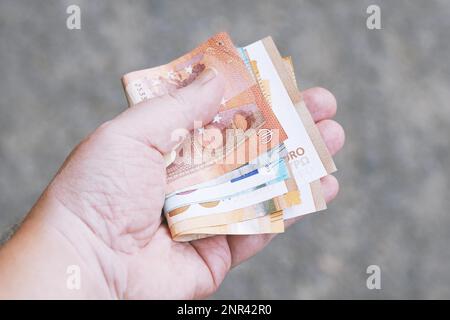 Hand, die eine Handvoll Euro Banknoten, Geld Finanzen Geschenke kaufen Ausgaben oder Kaufkraft Konzept Stockfoto