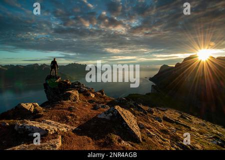 Ein Mann, der allein in den Sonnenuntergängen in den Bergen steht und aktiv im Freien wandert. Abenteuer-Lifestyle. Senja, Norwegen, Senja, Norwegen, Europa Stockfoto