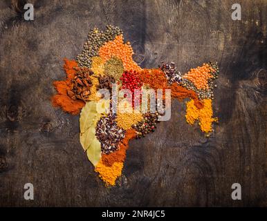 Karte von Indien aus verschiedenen traditionellen indischen Gewürzen, Reis, Linsen auf dunklem Holzhintergrund, Draufsicht. Gewürze und Zutaten zum Kochen Stockfoto