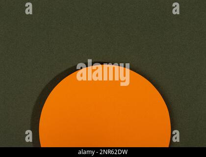 Abstrakter geometrischer Papierhintergrund. Orangefarbener Kreis mit Schatten auf dunkelgrünem Hintergrund. Stockfoto