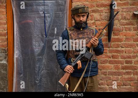 Srinagar, Indien. 25. Februar 2023. Ein indischer Polizist steht vor dem Haus von Sanjay Sharma Wache, einem kaschmirischen Hindu-Bankwächter, der von mutmaßlichen militanten Personen in Pulwama südlich von Kaschmir unter indischer Verwaltung erschossen wurde. Die Polizei sagte, dass mutmaßliche Militanten das Feuer auf Sanjay Sharma eröffneten, während er auf dem Weg zu einem lokalen Markt im Achan-Dorf Pulwama war. Kredit: SOPA Images Limited/Alamy Live News Stockfoto