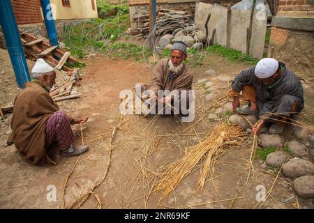 Srinagar, Indien. 25. Februar 2023. Muslimische Nachbarn von Kashmiri stellen Grasseile für den Sarg von Sanjay Sharma her, einem kaschmirischen Sicherheitsbeamten der Hindu-Bank, der in Pulwama südlich des indisch verwalteten Kaschmirs von mutmaßlichen Aktivisten erschossen wurde. Die Polizei sagte, dass mutmaßliche Militanten das Feuer auf Sanjay Sharma eröffneten, während er auf dem Weg zu einem lokalen Markt im Achan-Dorf Pulwama war. Kredit: SOPA Images Limited/Alamy Live News Stockfoto