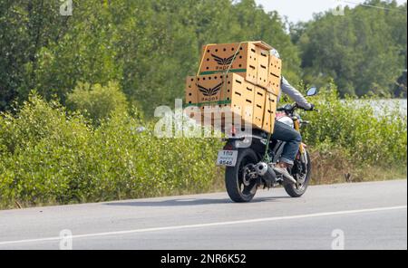 BANGKOK, THAILAND, FEBRUAR 07 2023, Ein Mann fährt Motorrad und transportiert lebende Hühner in Kartons Stockfoto