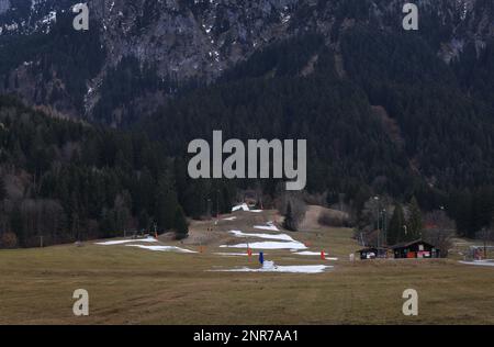 Schwangau, Deutschland. 23. Februar 2023. Überreste von künstlichem Schnee liegen auf einer Skipiste in einer grünen Landschaft. Angesichts der niedrigen Schneebedeckung in vielen Teilen der Alpen und des fehlenden Regenfalls im Februar sagen Experten, dass bald eine massive Dürre droht. (An dpa: "Erschreckend wenig Schnee: Massive Dürreperioden") Kredit: Karl-Josef Hildenbrand/dpa/Alamy Live News Stockfoto