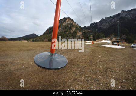 Schwangau, Deutschland. 23. Februar 2023. Die Schilder eines Schlepplifts hängen an einer Skipiste, auf der noch immer künstliche Schneereste zu sehen sind. Angesichts der oft niedrigen Schneedecke in den Alpen und des fehlenden Regenfalls im Februar sagen Experten, dass eine massive Dürre bevorsteht. (An dpa: "Erschreckend wenig Schnee: Massive Dürreperioden") Kredit: Karl-Josef Hildenbrand/dpa/Alamy Live News Stockfoto