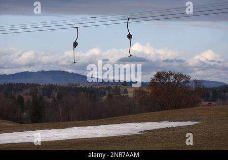 Schwangau, Deutschland. 23. Februar 2023. In der schneelosen Landschaft hängen die Schilder eines Schlepplifts über einem künstlichen Schneestreifen. Angesichts der niedrigen Schneebedeckung in vielen Teilen der Alpen und des fehlenden Regenfalls im Februar sagen Experten, dass bald eine massive Dürre droht. (An dpa: "Erschreckend wenig Schnee: Massive Dürreperioden") Kredit: Karl-Josef Hildenbrand/dpa/Alamy Live News Stockfoto