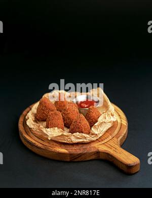Frittierter, knuspriger Camembert mit Cranberry-Sauce in einer dekorativen Pfanne auf Holzhintergrund. Stockfoto