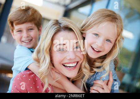 Besondere Momente wie diese bringen immer Lächeln. Porträt einer Mutter und ihrer beiden Kinder, die draußen schöne Zeit miteinander verbringen. Stockfoto