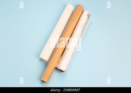Rollen aus Aluminiumfolie und Backpapier auf blauem Hintergrund Stockfoto