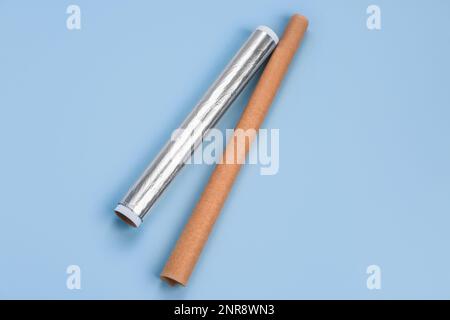 Rollen aus Aluminiumfolie und Backpapier auf blauem Hintergrund Stockfoto