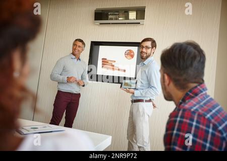 Der Beweis ist im Gange. Zwei Geschäftsleute, die ihren Kollegen bei der Arbeit eine Präsentation halten. Stockfoto