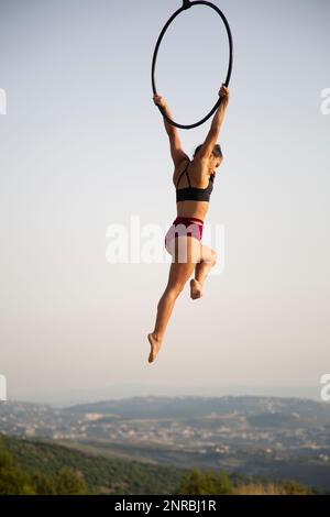 Junge weibliche Aerialistin, die draußen im Korb spielt Stockfoto