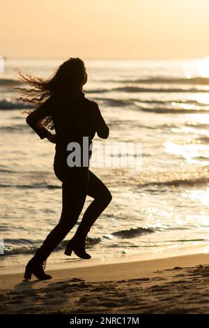 Eine Frau, die am Strand wegläuft Stockfoto