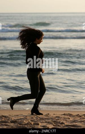 Eine Frau, die am Strand wegläuft Stockfoto
