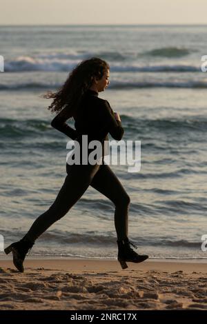 Eine Frau, die am Strand wegläuft Stockfoto