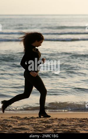 Eine Frau, die am Strand wegläuft Stockfoto
