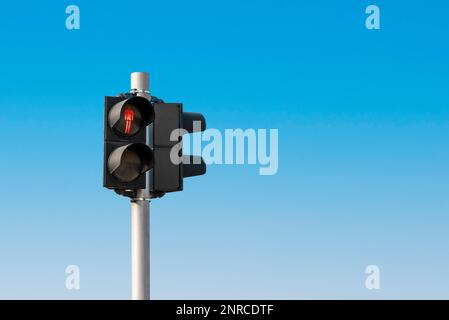 Rotes Fußgängerlicht vor einem wolkenlosen blauen Himmel Stockfoto