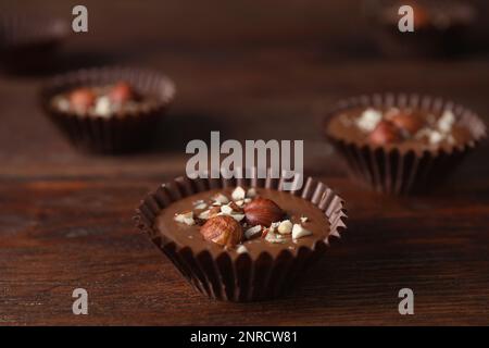 Köstliche Schokoladenbonbons mit Haselnüssen auf einem Holztisch, Nahaufnahme Stockfoto