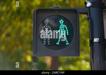 Nahaufnahme einer grünen Fußgängerampel an einem Fußgängerübergang. Stockfoto