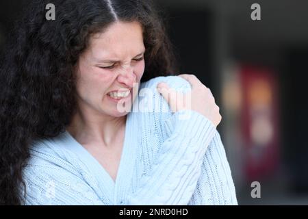 Frau mit Schulterschmerzen, die sich auf der Straße beschwert Stockfoto
