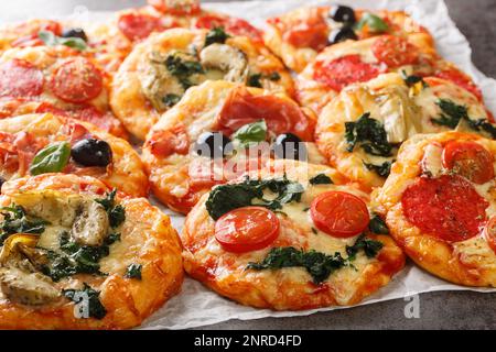 Pizzette italienische Mini-Pizzas oder Pizzabisse aus der Nähe von Pergament auf dem Tisch. Horizontal Stockfoto