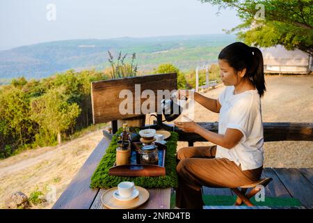 Frauen, die in den Bergen Thailands Kaffee machen. Eine Asiatin, die Kaffee in einem Zeltlager zubereitet Stockfoto