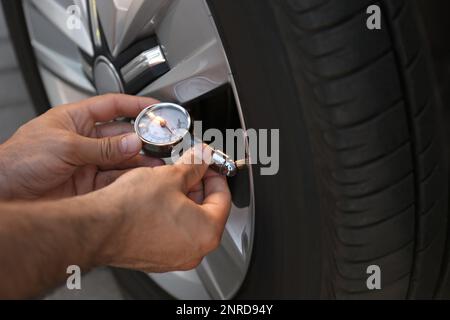 Ein Mann, der den Luftdruck im Autoreifen überprüft, Nahaufnahme Stockfoto