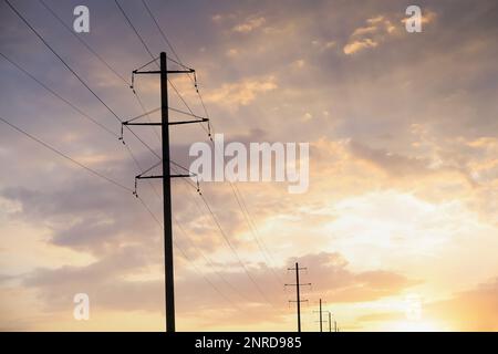 Telefonmasten und Kabel gegen blauen Himmel mit Wolken Stockfoto