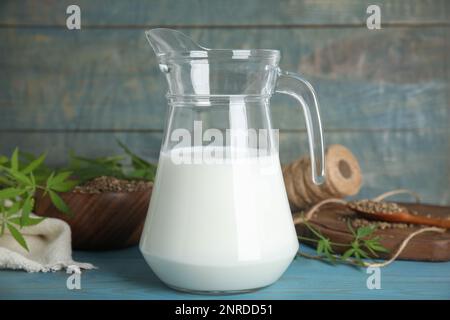 Krug mit Hanfmilch auf hellblauem Holzhintergrund Stockfoto