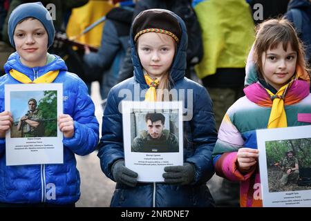 Holland Park, London, 24/2/23. Junge Ukrainer posieren für die Medien, während sie Fotos von Opfern der russischen Invasion/Besetzung am Jahrestag 1. halten Stockfoto