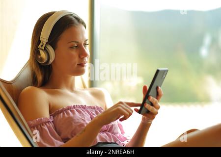 Teenager, die zu Hause auf einem Stuhl Musik hören Stockfoto