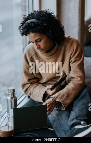 Unternehmerin, die sich ein Tagebuch ansieht, während sie mit einem Tablet-PC am Fenster im Kreativbüro sitzt Stockfoto