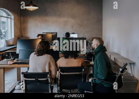 Programmiererinnen und Programmiererinnen, die während ihrer Arbeit bei einer Startup-Firma am Computer codieren Stockfoto