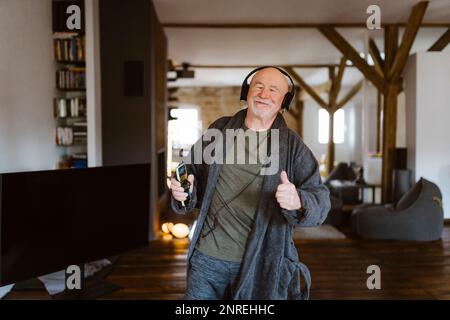 Seniorenmensch, während Sie zu Hause Musik über Kopfhörer hören Stockfoto