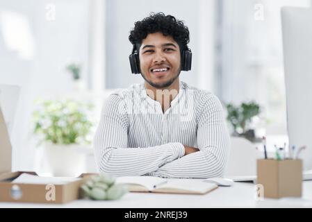 Er ist ein cooler und selbstbewusster Kerl. Porträt eines jungen Geschäftsmannes, der während der Arbeit im Büro Kopfhörer trägt. Stockfoto