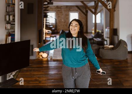 Sorgenfreie Frau, die zu Hause tanzt und Musik im Wohnzimmer hört Stockfoto