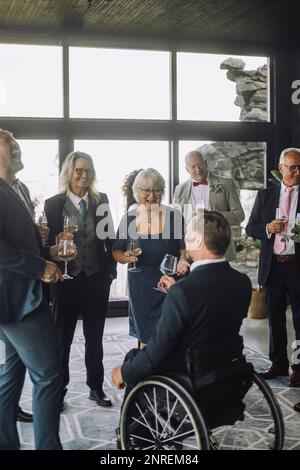 Männliche und weibliche Gäste aus verschiedenen Rassen, die bei der Hochzeitszeremonie einen Drink zu sich nehmen Stockfoto