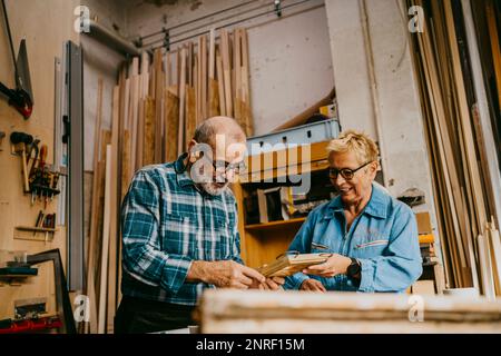 Männliche und weibliche Senior Entrepreneure, die über Rahmen in der Werkstatt diskutieren Stockfoto